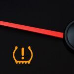 A car's dashboard displaying a tire pressure warning light illuminated in red.